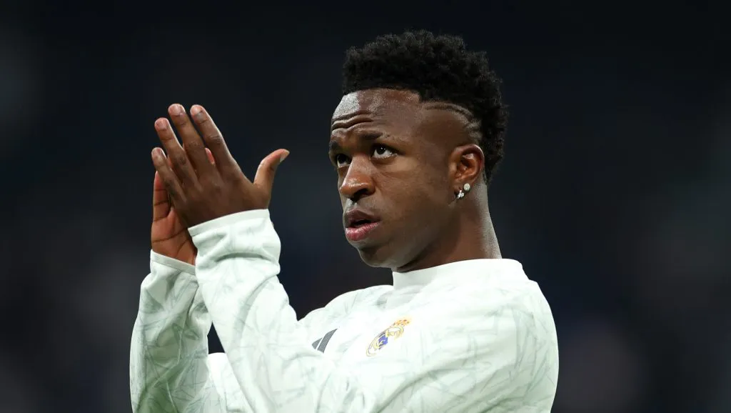 Vinícius Júnior aplaude com olhar para cima em direção à arquibancada durante aquecimento do Real Madrid
