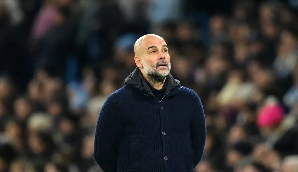 Guardiola com os braços para trás na área técnica (Michael Regan/Getty Images)