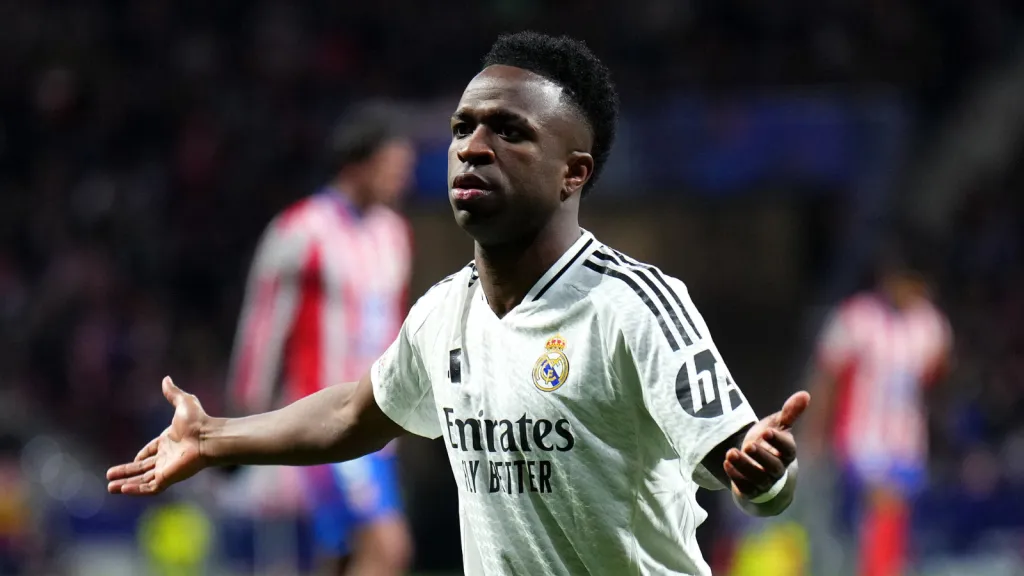 Vinicius Júnior com os braços abertos durante partida do Real Madrid