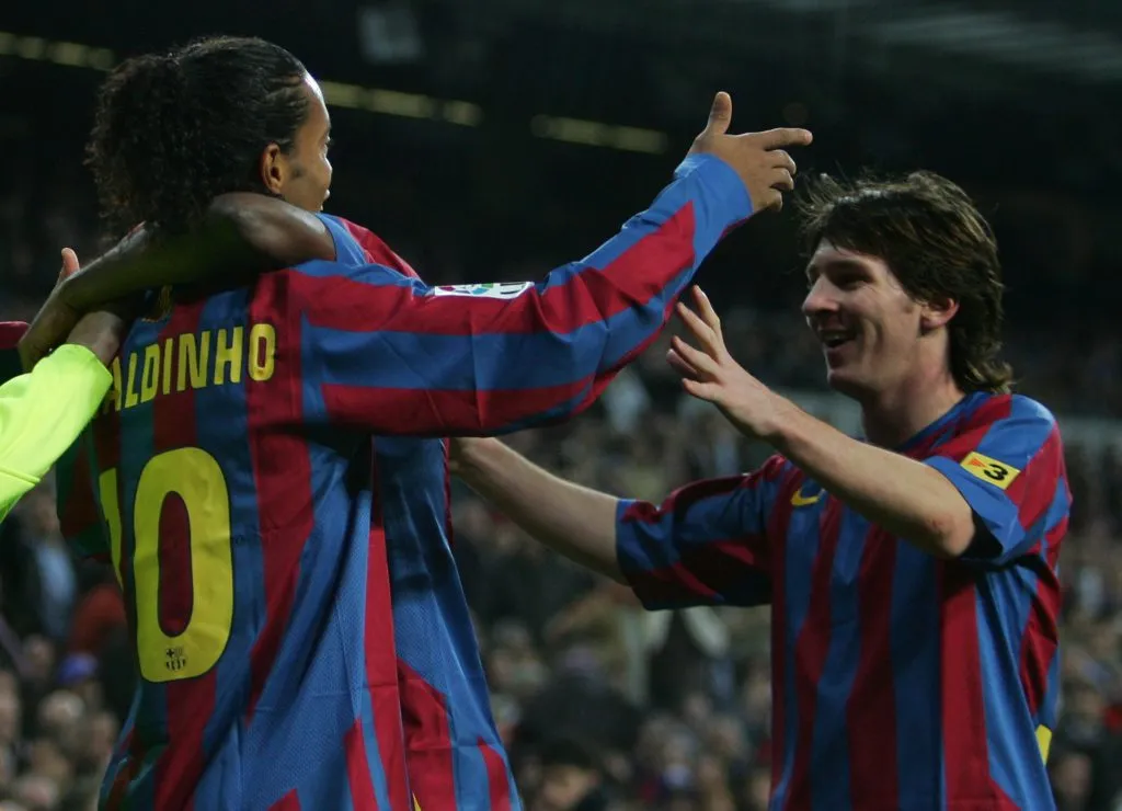 Ronaldinho (à esquerda), do Barcelona, comemora com Lionel Messi após marcar um gol durante a partida da La Liga entre Real Madrid e F.C. Barcelona no Estádio Santiago Bernabéu, em 19 de novembro de 2005, em Madri, Espanha. (Foto de Denis Doyle/Getty Images)