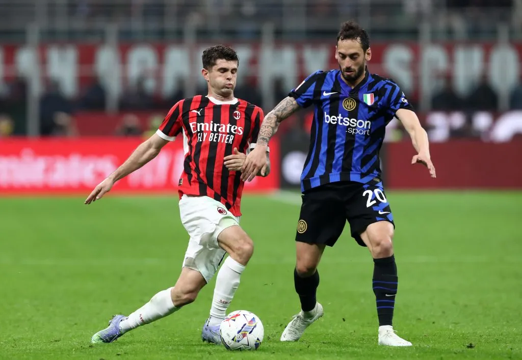 Christian Pulisic, do AC Milan, tenta passar por Hakan Calhanoglu, da Internazionale, durante a partida da semifinal da Coppa Italia entre AC Milan e Internazionale, no Estádio Giuseppe Meazza, em 2 de abril de 2025, em Milão, Itália. (Foto de Marco Luzzani/Getty Images)