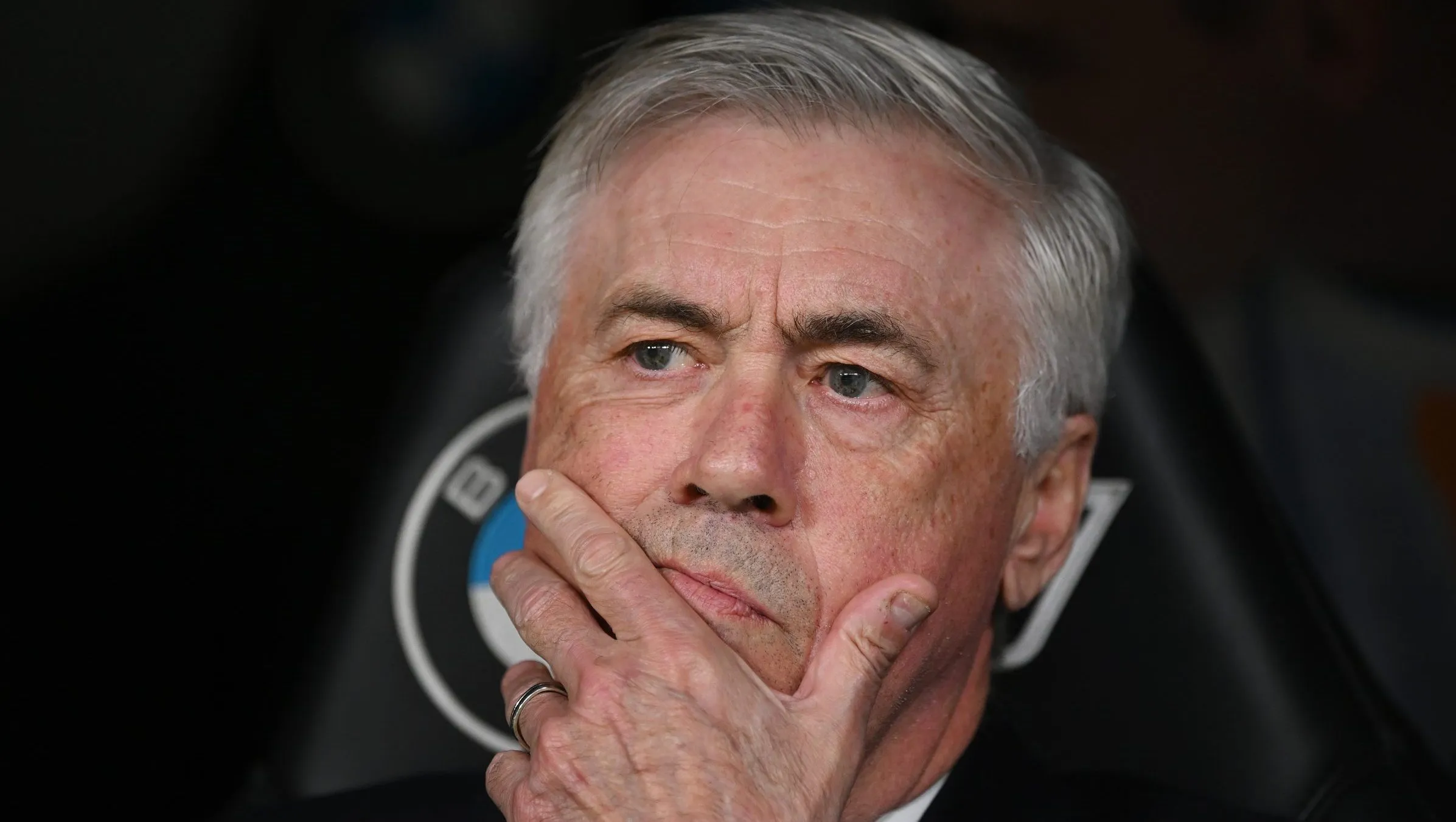 Ancelotti, de terno preto, sentado no banco de reservas (Photo by Denis Doyle/Getty Images)