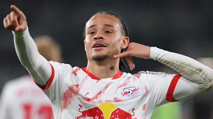 Xavi Simons, com uma mão na orelha e outra apontando para frente, com a camisa branca do RB Leipzig
