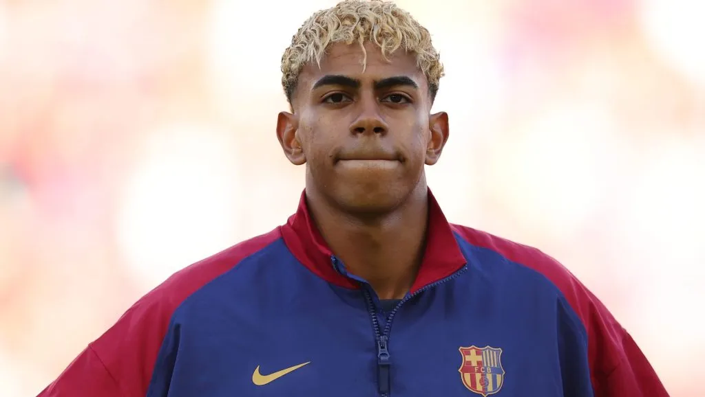 Lamine Yamal, em campo, cm a jaqueta azul e vinho do Barcelona (Photo by Florencia Tan Jun/Getty Images)