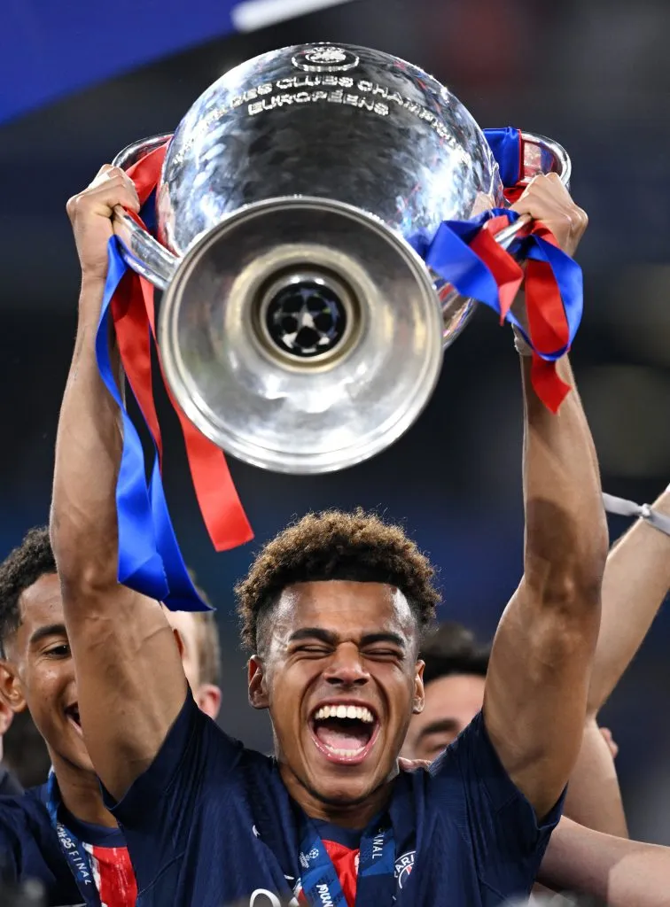 Doué, segurando a taça, com a camisa azul 