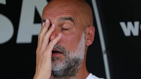 Guardiola, treinador do Manchester City, sentado no banco de reservas.