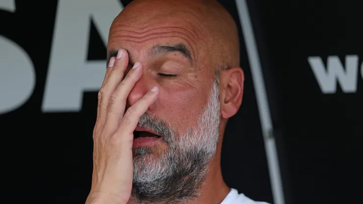 Guardiola, treinador do Manchester City, sentado no banco de reservas.