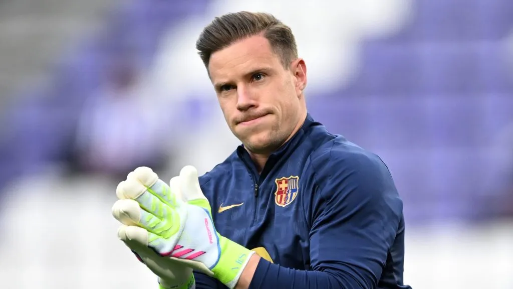 Ter Stegen, em cmpo, com jaqueta azul e luva branca com verde
