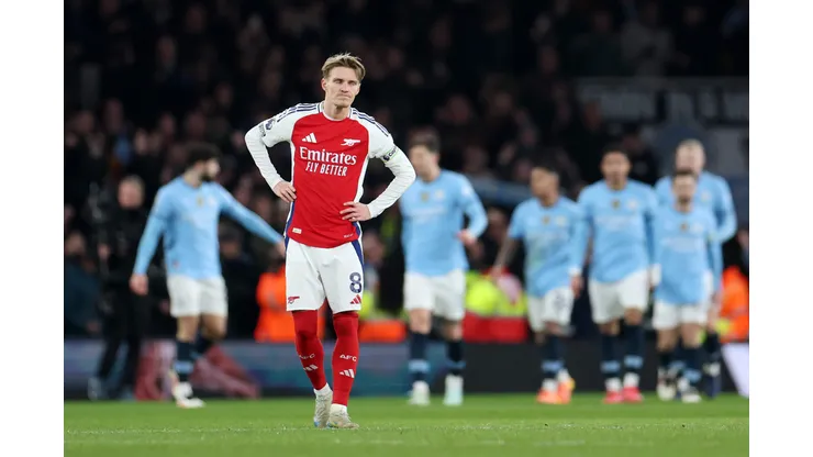 Martin Odegaard, do Arsenal, parece abatido enquanto Erling Haaland, do Manchester City (obscurecido), comemora o primeiro gol de sua equipe com seus companheiros durante a partida da Premier League entre Arsenal FC e Manchester City FC no Emirates Stadium em 02 de fevereiro de 2025 em Londres, Inglaterra. Foto: Alex Pantling/Getty Images
