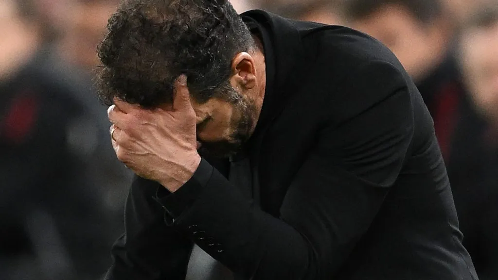Diego Simeone, técnico do Atlético de Madrid, de cabeça baixa e mão no rosto na beira do campo. Foto: Clive Mason/Getty Images