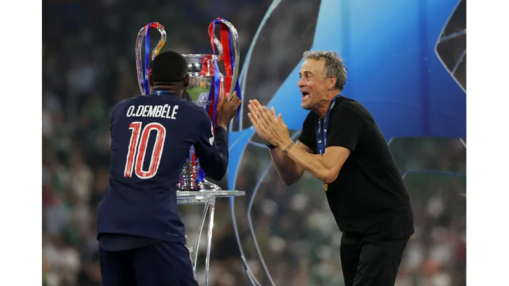 Ousmane Dembélé, do Paris Saint-Germain, beija o troféu da Liga dos Campeões da UEFA, enquanto Luis Enrique, técnico do Paris Saint-Germain, comemora após a vitória da equipe, garantindo ao Paris Saint-Germain o primeiro título da Liga dos Campeões da UEFA na história do clube e um recorde de vitórias na final da Liga dos Campeões da UEFA, com placar de 5 a 0, após a final da Liga dos Campeões da UEFA de 2025 entre Paris Saint-Germain e FC Internazionale Milano na Munich Football Arena em 31 de maio de 2025 em Munique, Alemanha. Foto: Carl Recine/Getty Images
