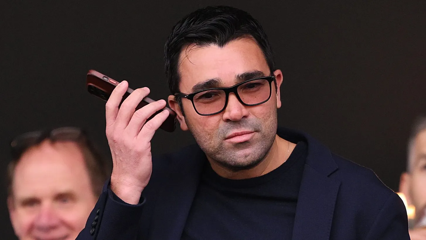 Deco, falando ao telefone, de terno preto