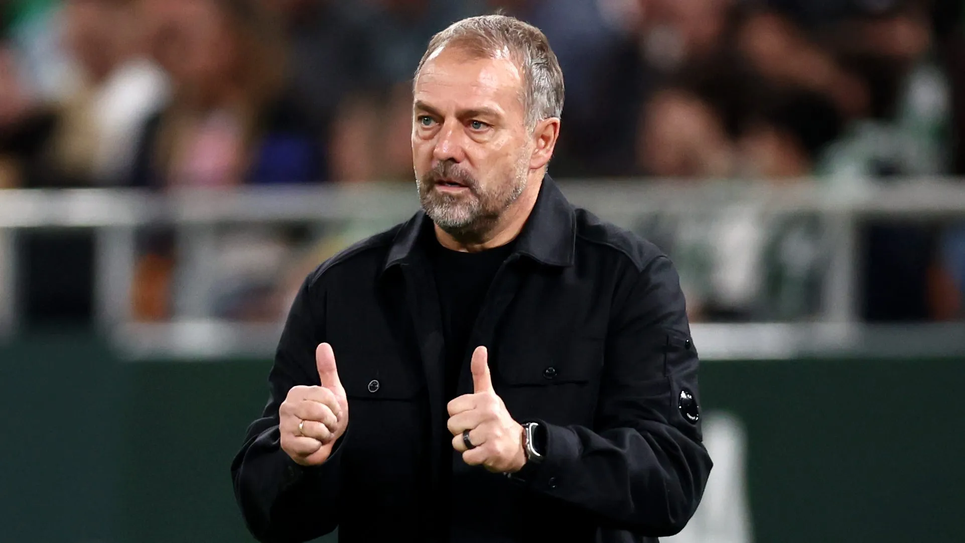 Hansi Flick fazendo joia com um casaco preto em jogo do Barcelona