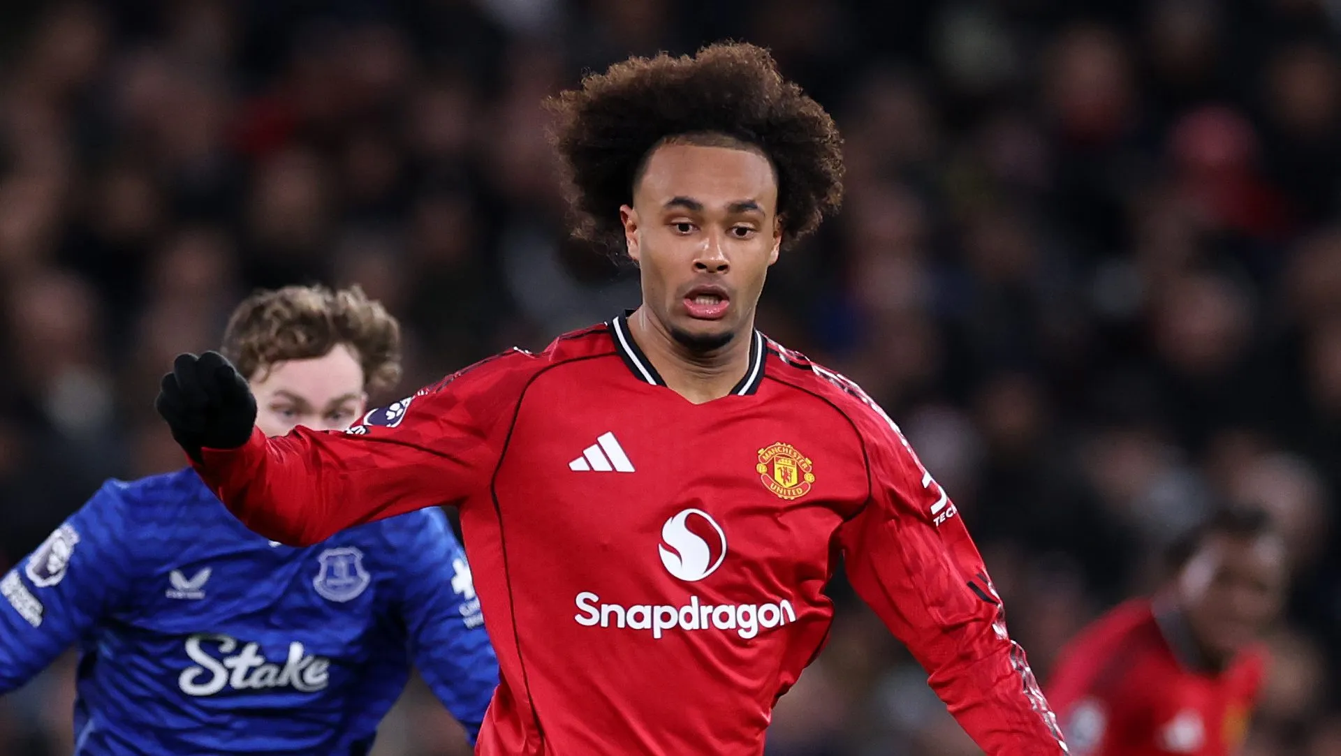 Zirkzee correndo com a camisa vermelha e uniforme branco do United