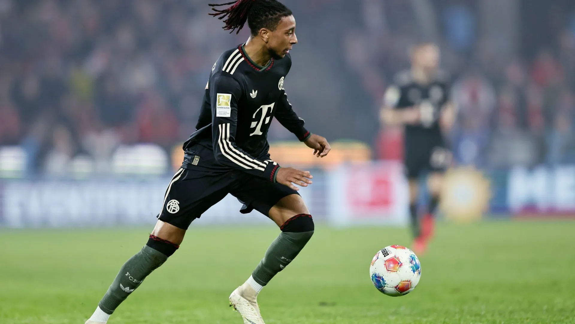 Michael Olise corre com a bola durante partida da Bundesliga. Foto: Christof Koepsel/Getty Images