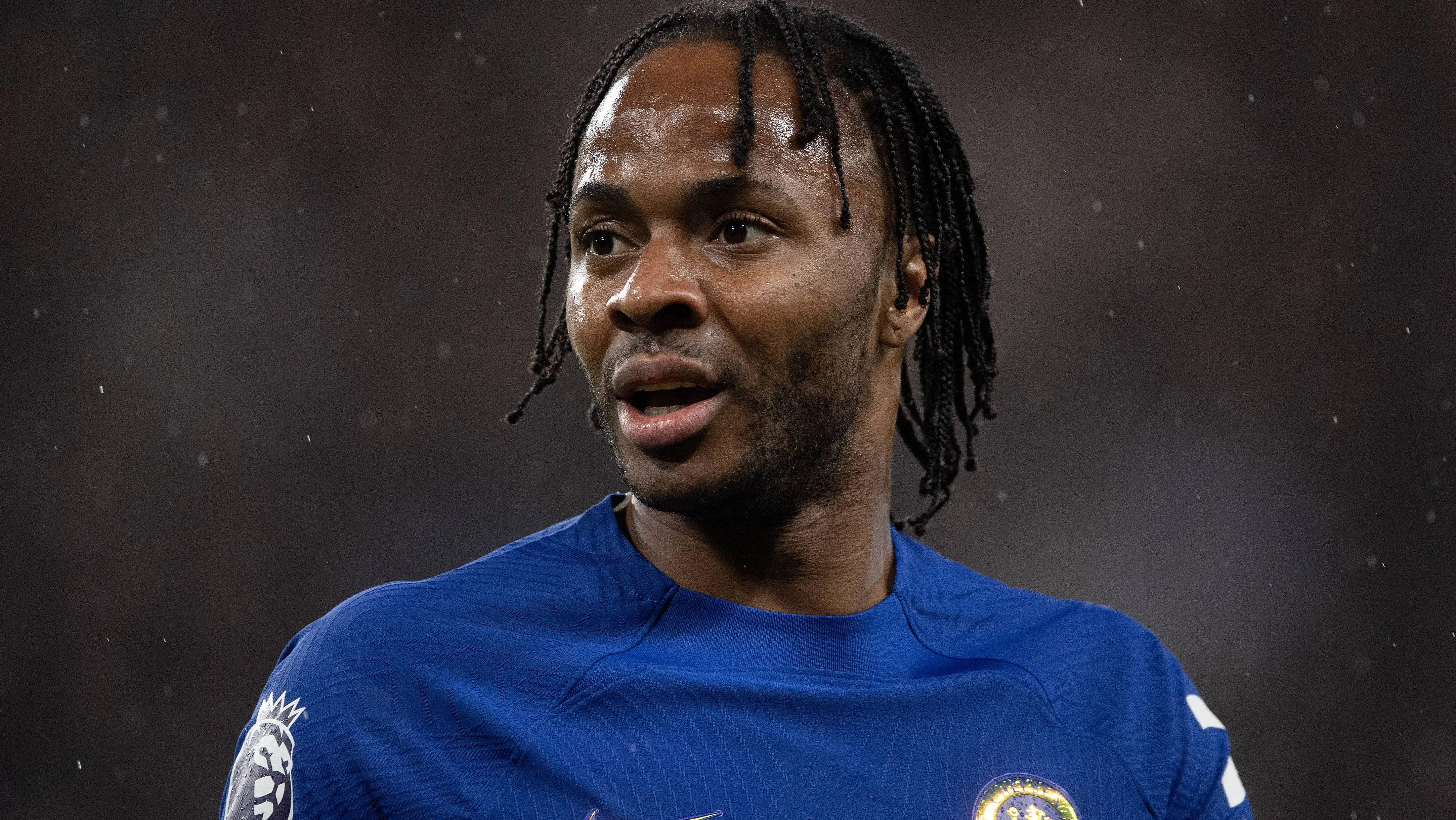 Sterling, em campo, de camisa azul do Chelsea