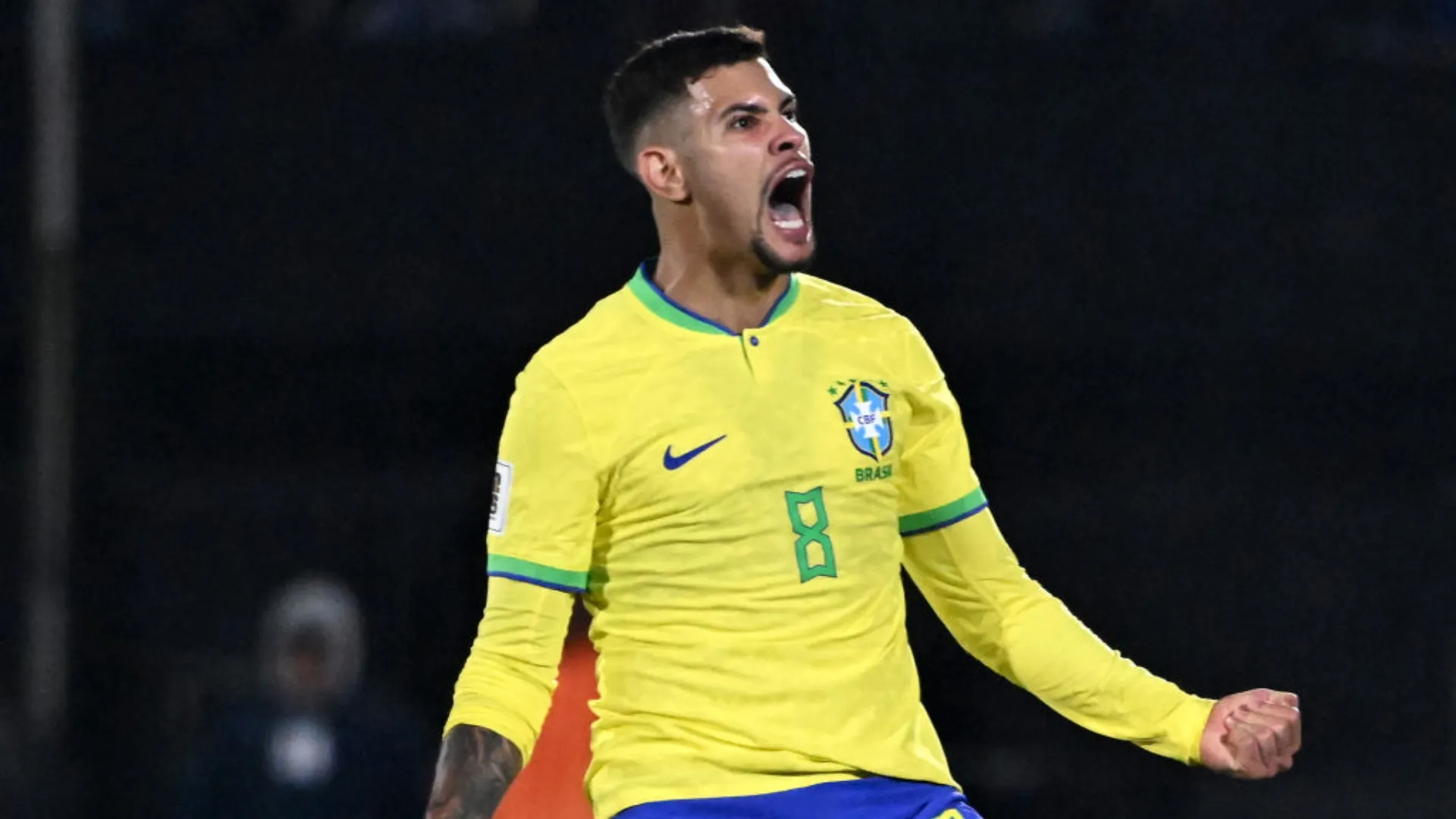 Bruno Guimarães comemora gol pela Seleção Brasileira; jogador aparece com a boca aberta enquanto grita