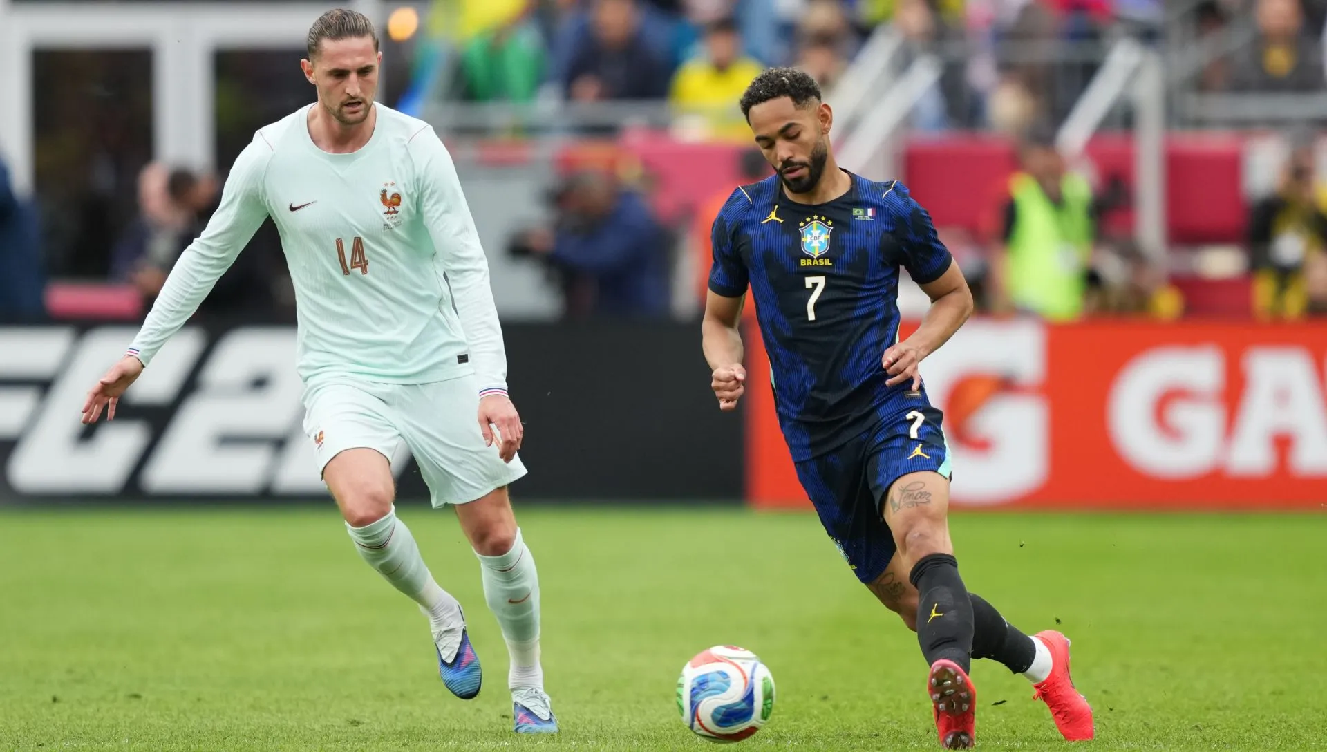 Matheus Cunha corre com a bola contra Adrien Rabiot durante amistoso.