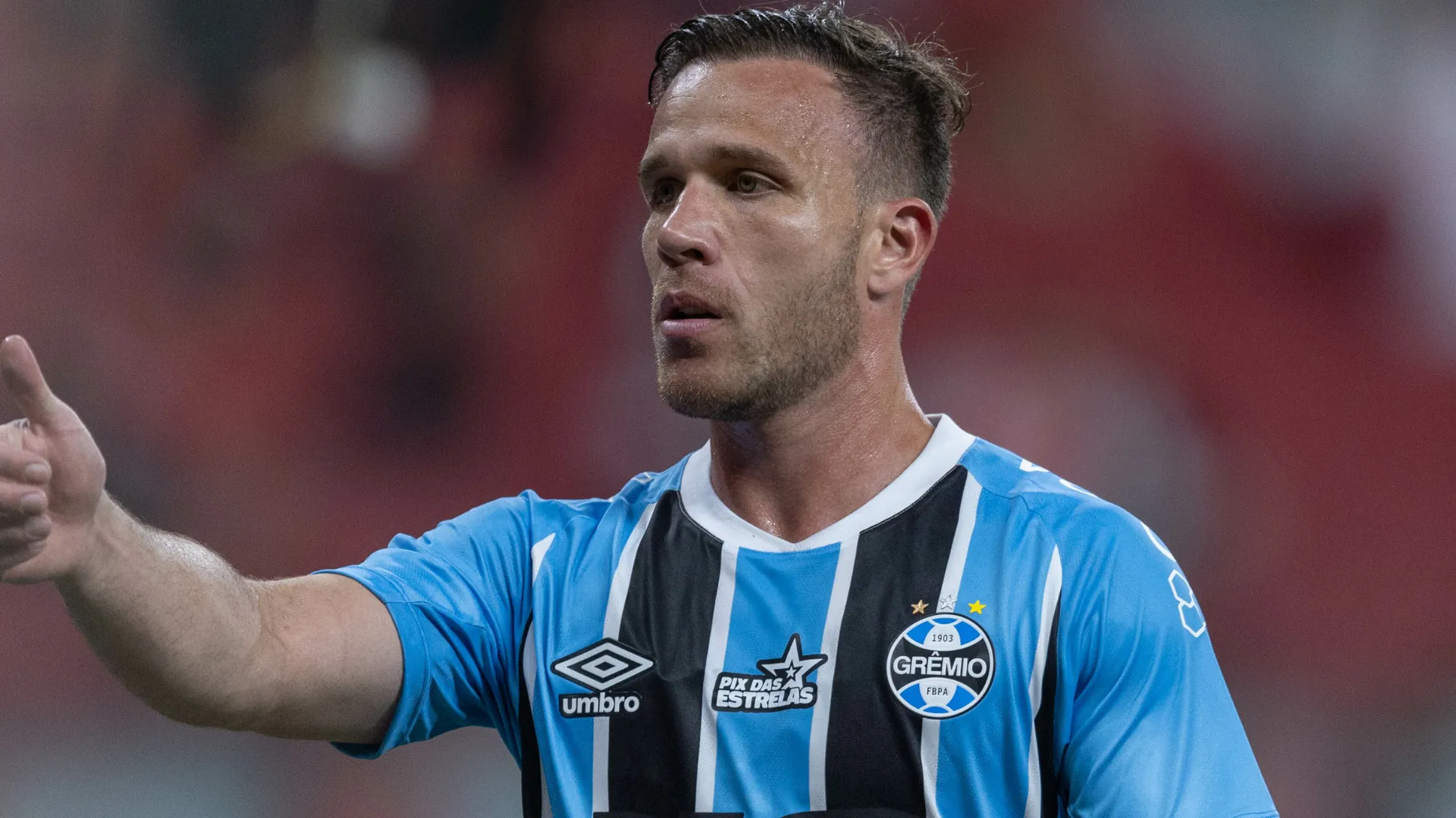 Arthur aparece fazendo sinal positivo durante uma partida pelo Grêmio