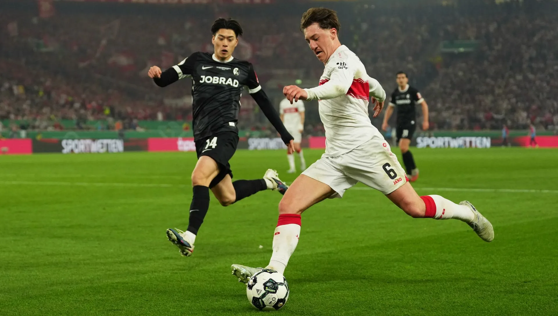 Angelo Stiller cruza bola sob pressão de Yuito Suzuki durante partida da Copa DFB. Foto: Sona Maleterova/Getty Images