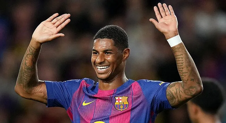 Marcus Rashford sorrindo com as mãos para o alto